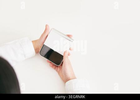 A person holds a smartphone with the screen locked, showing a blank screen and a time display. Stock Photo