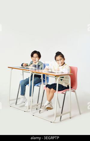Two students in a classroom, smiling at the camera while studying together. Stock Photo