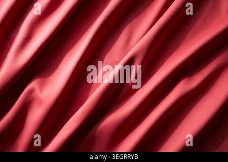 A close-up of a red silk fabric, gently crumpled and softly lit. Stock Photo