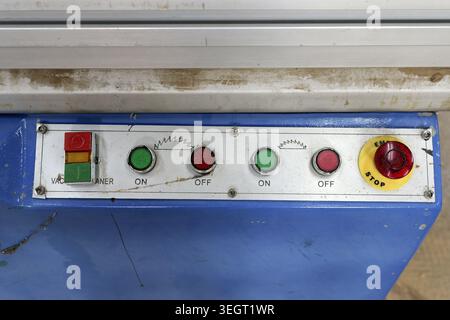 Control panel displaying power on and off buttons for an industrial saw machine, featuring an emergency stop button for workplace safety and equipment Stock Photo