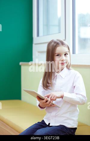 a girl using tablet PC while sitting Stock Photo