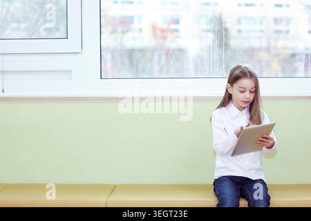 a girl using tablet PC while sitting Stock Photo
