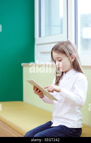 a girl using tablet PC while sitting Stock Photo
