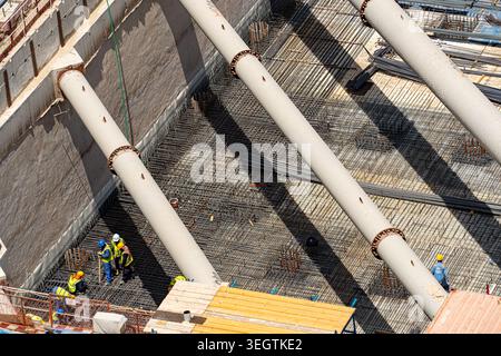Aerial view of construction workers in safety gear working on a steel rebar foundation with large white support struts in Dubai, Dubai, United Arab Em Stock Photo