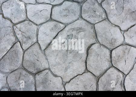 Close up view of solid grey stone texture background showing rough concrete pavement pattern with calm irregular shapes and dark mortar lines creating Stock Photo