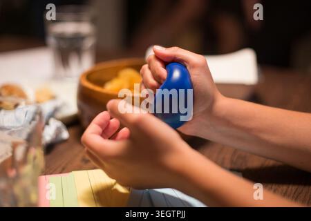 A woman squeezes a stress ball while surrounded by snacks and notebooks, while she works on a script Stock Photo