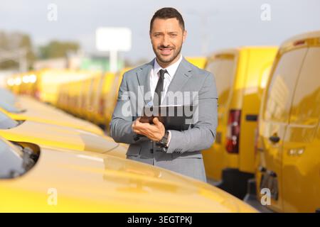 Fleet manager writing on a clipboard in front of a yellow vans Stock Photo