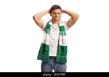 Disappointed football fan with a green and white scarf holding his hands behind his head isolated on white background Stock Photo