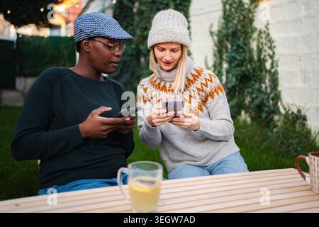 Two diverse friends connecting using smartphones outdoors Stock Photo