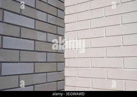 Corner of a building displaying brick walls with different colors and patterns. Gray and white bricks forming a textured architectural surface Stock Photo