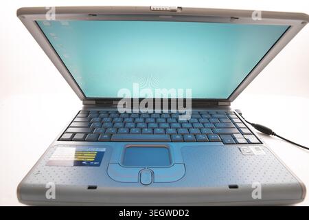 A laptop sits open on a white desk, its screen displaying a blank, light blue desktop background. Stock Photo