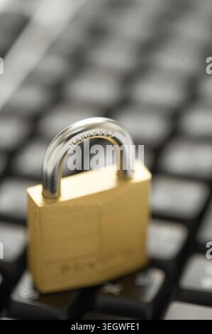 A gold padlock lies on a computer keyboard, secure in its position. Stock Photo