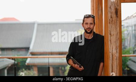 Man architect holding tablet on outdoor balcony with traditional buildings Stock Photo