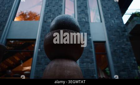 Modern abstract sculpture featuring stacked stone elements against contemporary building facade Stock Photo