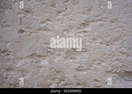 Rough beige stone wall background with pits and weathered architectural texture Stock Photo
