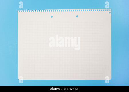 Single blank spiral notebook with grid pattern on bright blue background. Clean, minimalist composition perfect for education, office supplies, and st Stock Photo