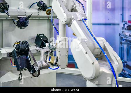 Industrial robotic arm polishing metal part in modern automated factory workstation. Stock Photo