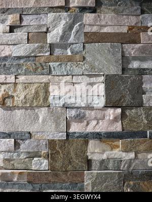 Wall covering made of natural stones strips of different types and colors. Full frame. Background and texture, vertical shape. Stock Photo