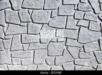 Prefab concrete wall with a texture that imitates a stone wall with irregular shaped rocks. Full frame, background and texture. Stock Photo