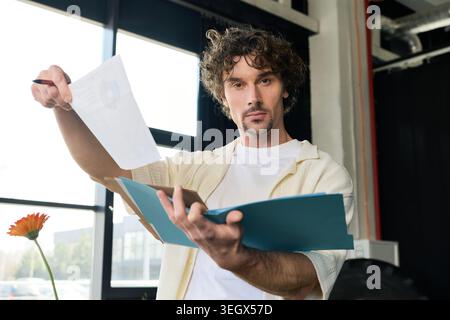 Young, handsome man in a stylish office reviews documents while working. Stock Photo