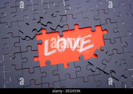 A missing piece of a jigsaw puzzle with the word "LOVE" written on it, surrounded by a sea of unconnected pieces. Stock Photo