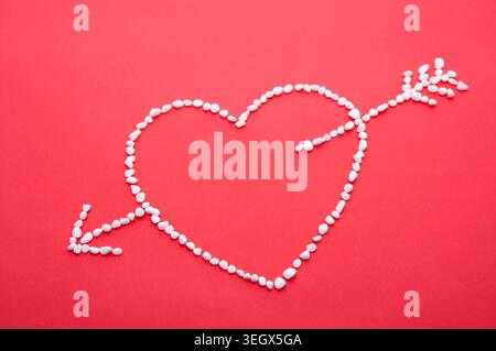 A heart made of small white stones is formed on a red background. Stock Photo