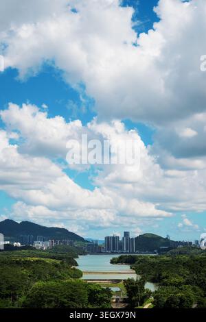 Vertical composition lake view with bright blue sky and prominent white clouds, lychee forest, Shenzhen, Landscape in China Stock Photo