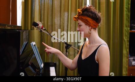 Female musician using tablet for sheet music while preparing to play piano in studio Stock Photo