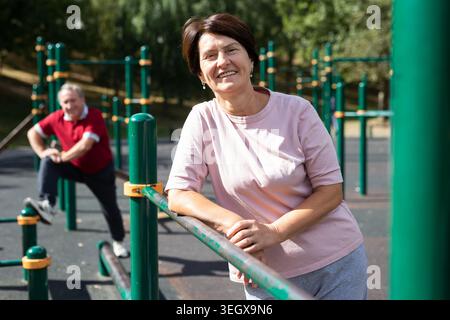 elderly woman stands at a sports bar on an outdoor sports field Stock Photo