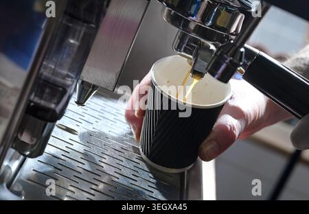 barista making coffee in cardboard cup on coffee machine Stock Photo