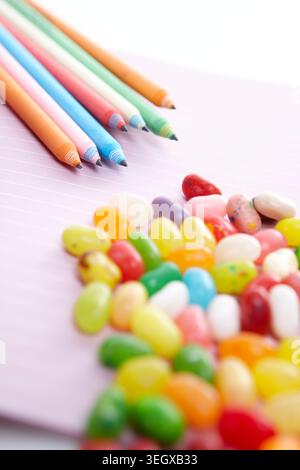 Pink Note Book With Various Colors Of Pencils And Jelly Beans Stock Photo