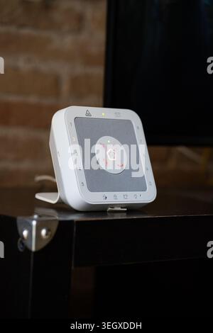 White smart home security hub displaying a central illuminated status light Stock Photo