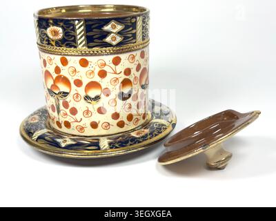 Antique English porcelain jam pot jar with lid featuring hand-painted red and blue Imari pattern with gold detailing on white background Stock Photo