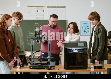 Teacher Guiding Teenagers Using 3d Printers in Stem Classroom Stock Photo