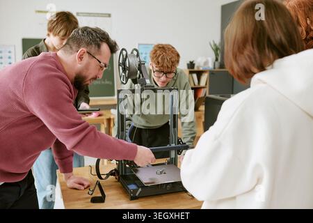 Teacher and Teenagers Operating 3d Printer in Stem Classroom Stock Photo