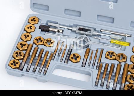 Professional tap and die set with titanium-coated thread cutting tools organized in a gray plastic case. Stock Photo