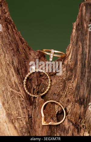 Three gold rings with diamonds displayed on a natural textured tree bark background. Stock Photo