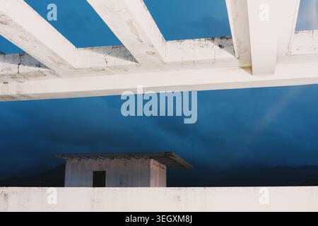 White wooden beams frame a dramatic twilight sky above a minimalist concrete structure Stock Photo
