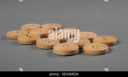 Natural wooden sewing buttons arranged on gray background for tailoring, textile craft and garment accessories Stock Photo