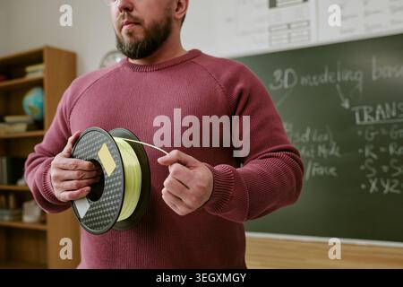 Middle Aged Man Holding 3d Printer Filament in Classroom Stock Photo