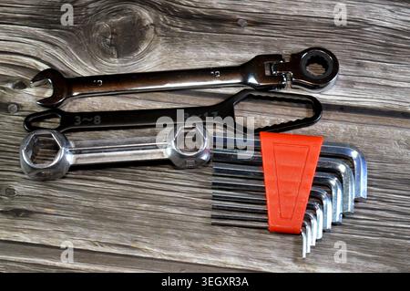 a set of hand tools including a flexible head ratcheting wrench, a specialized flat wrench, and a set of Allen keys Stock Photo