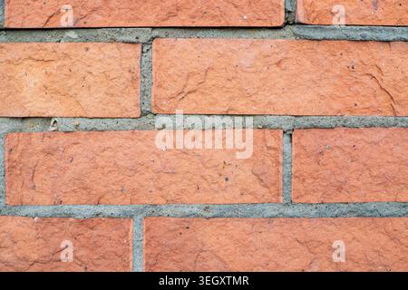 Red clay brick wall texture. Rough surface of a traditional ceramic block structure. Durable construction material used for exterior property facades Stock Photo