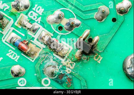 Close-up view of a damaged electronic circuit board with burnt components and corrosion Stock Photo