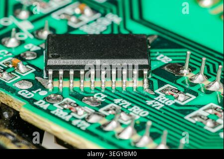 Close-up macro view of a black integrated circuit chip on a green printed circuit board Stock Photo