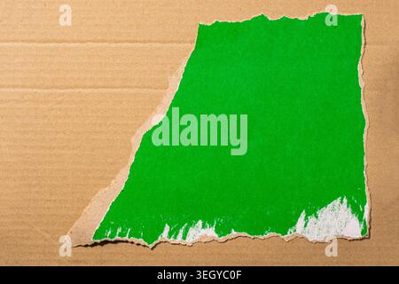 Ripped corrugated cardboard revealing a vibrant green screen background, providing unique texture and copy space for design mockups Stock Photo