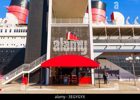 Exterior view of the Queen Mary entrance sign and funnels at the waterfront in Long Beach, California under a clear blue sky. Stock Photo