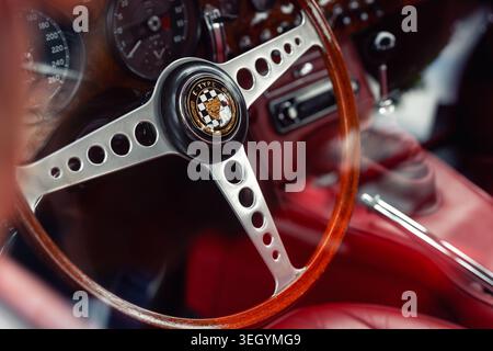 Leipzig, Germany - 9 May, 2026. Closeup view Jaguar E-Type steering wheel wooden rim chrome detail red leather interior vintage sportscar cockpit Stock Photo