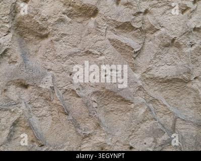 Closeup Sunlit Sandstone Wall Showing Angular Relief And Granular Surface, Warm Beige Tones, Shallow Shadowed Crevices, Natural Erosion Grooves, High Stock Photo