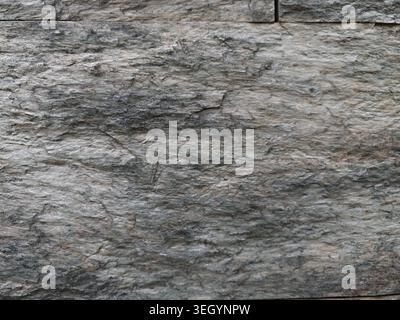 Coarse Granite Wall With Layered Striations, Natural Gray Tones, Rugged Relief, Micro Fissures And Mineral Grains, Matte Finish, Durable Texture Ideal Stock Photo