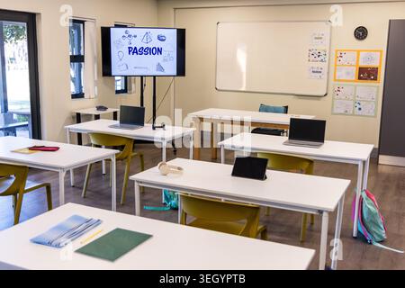 Empty classroom showing white tables, mustard chairs, laptops, tablet, monitor reading PASSION Stock Photo